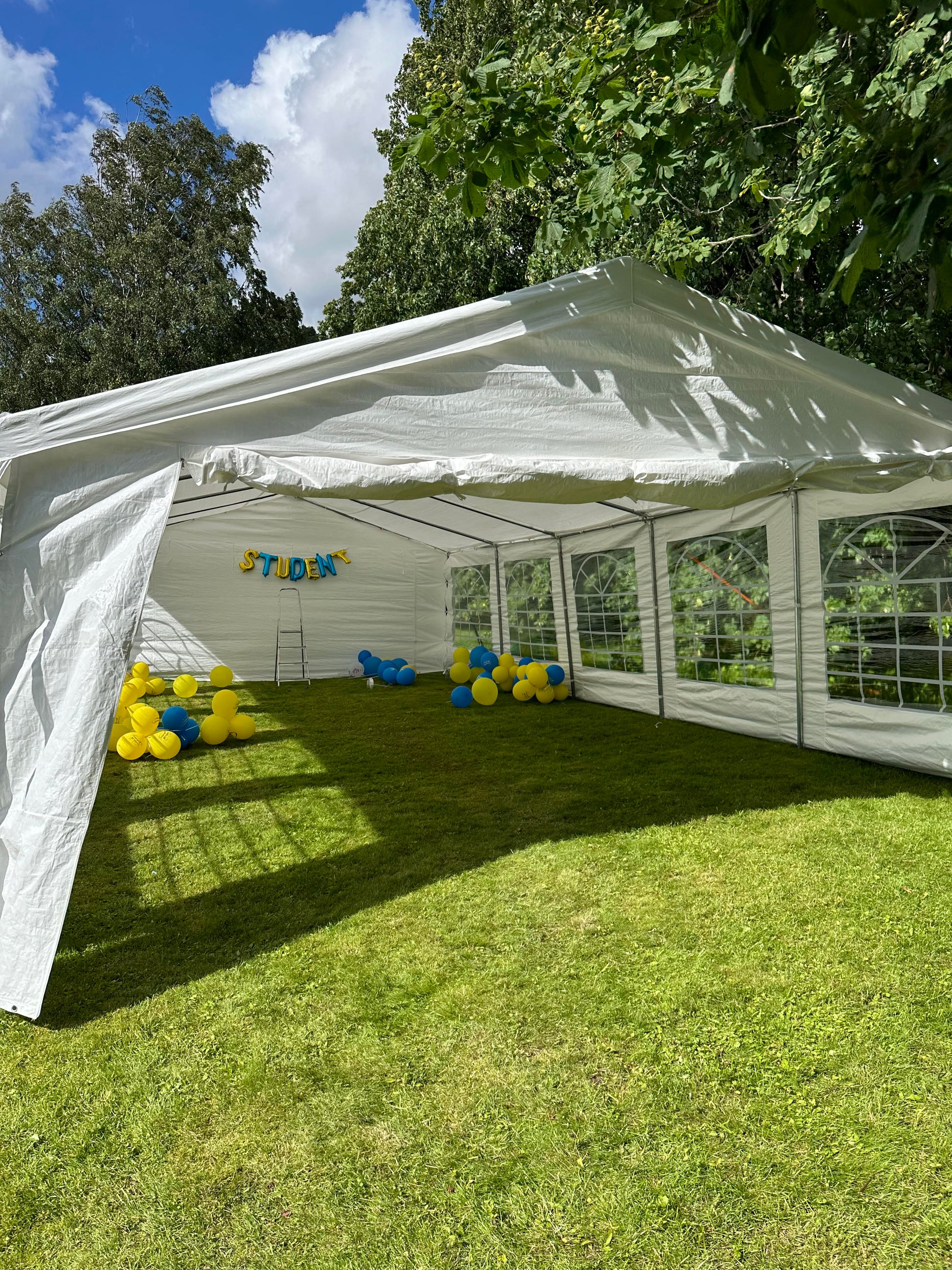 Partytält 5x10 uppsatt på en gräsmatta.